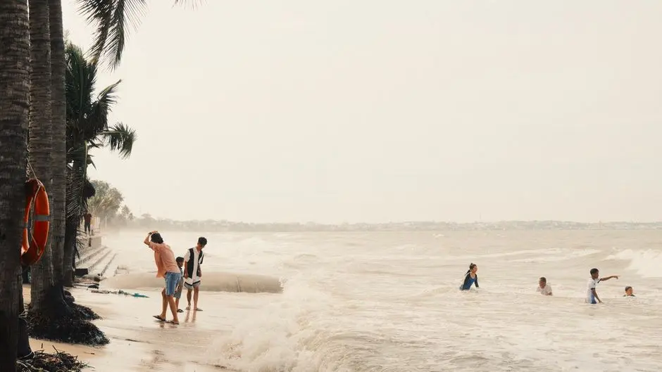 Pantai Carita dengan pasir putih dan ombak tenang, keluarga bermain di tepi pantai
